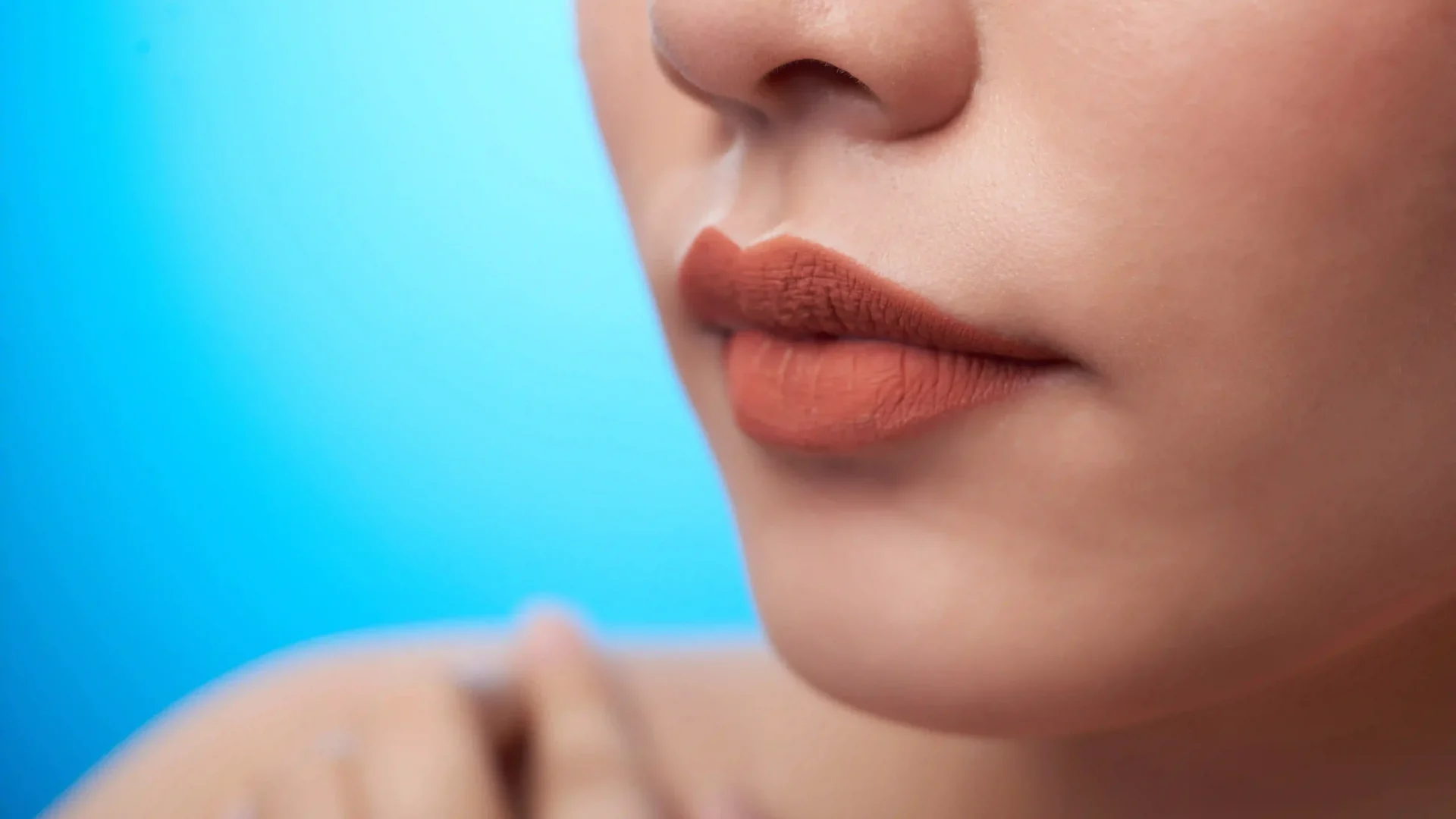 extreme-closeup-female-mouth-with-lipstick-nose-fingers-touching-bare-shoulder-blue